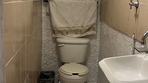 A small, compact bathroom with a toilet, sink, and tiled floor.
