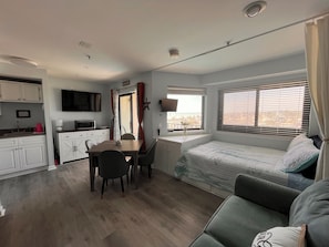 A compact living space with a kitchenette, dining area, and a bed with a view. - Bubbles Up! Cozy condo in a perfect oceanfront location with amazing amenities (Myrtle Beach)