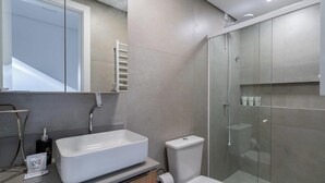 Et moderne badeværelse med en stor, hvid vask, toilet og en brusekabine med glasvægge.