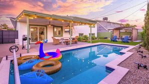 Un jardin avec une piscine, des flamants gonflables et du mobilier d’extérieur.