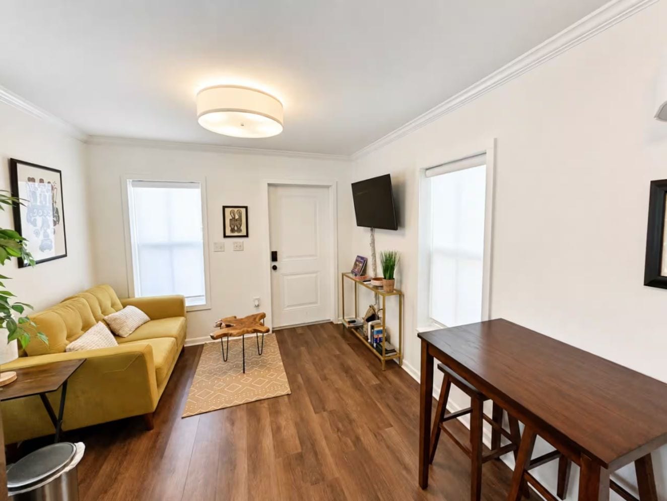 Een woonkamer met een bank, salontafel en een aan de muur bevestigde televisie.