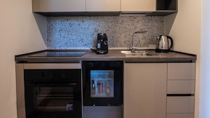 A compact kitchen with a built-in oven, a coffee maker, and a kettle on the countertop. - Charming elegant room in central Acireale with serene garden view (Acireale)
