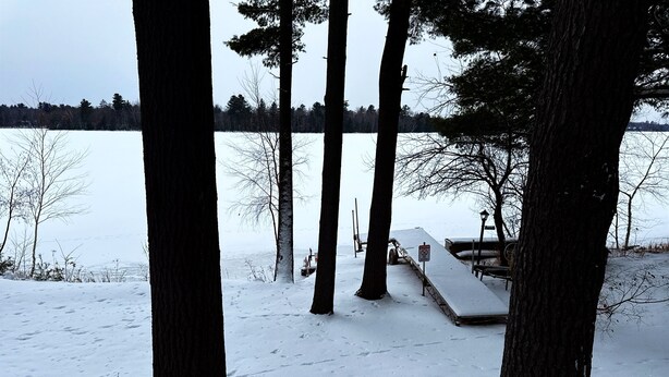 A snowy outdoor area with a dock and a boat. - Foster's Lakeside - Sandy Shore with Snowmobile Access & Year-Round Fun (Tomahawk)