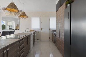 A modern kitchen with a central island, stainless steel appliances, and a view of the outdoors. - 3306 (Mijas Costa)