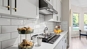 A modern kitchen with white cabinets, a stainless steel stove, and a window with a view of greenery. - Private Pool, Chefs Kitchen & Patio Near Old Town Scottsdale Desert Luma by Avantstay (Scottsdale)