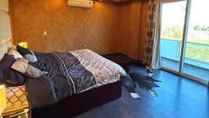 A modern bedroom with a large bed, a ceiling light fixture, and a large window.