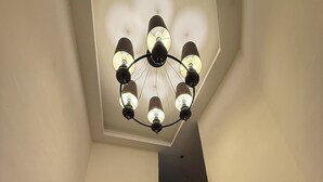 A staircase with blue LED lighting, a chandelier with multiple bulbs, and a door at the top.
