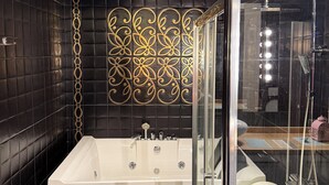 A modern bathroom with a large bathtub, a glass-enclosed shower, and a decorative wall panel.