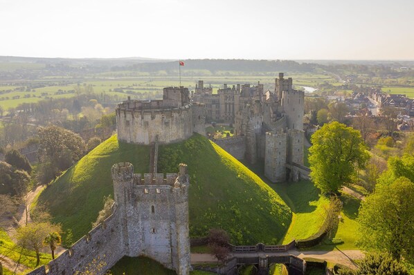 A historic castle with a prominent tower, surrounded by lush green fields and a small village in the background. - Coastal Comfort for 6 Felpham Beach (Bognor Regis)