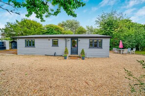 A single-story house with a gravel driveway, a front door, and two potted plants. - Sidlesham Hideaway Logburner Garden (Chichester)