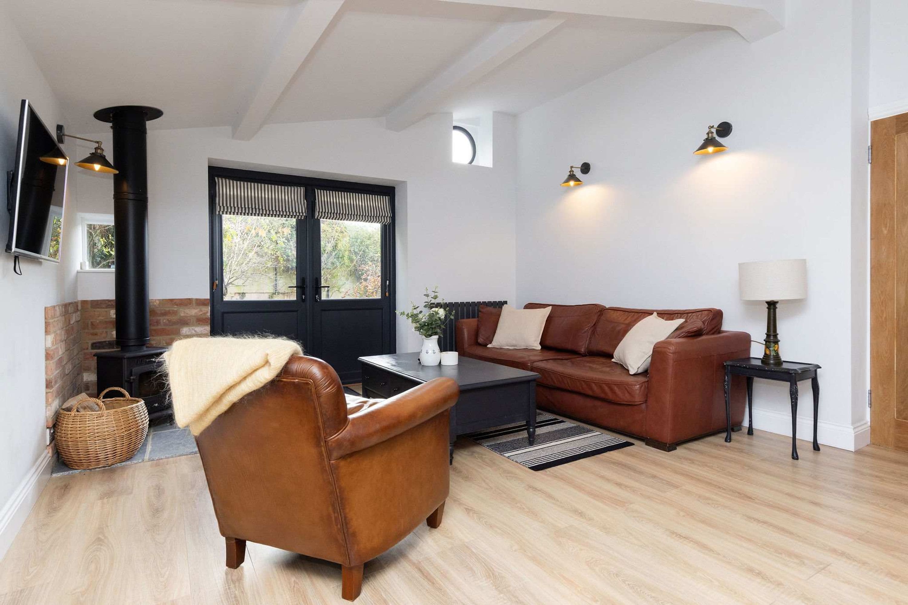 A modern living room with a leather sofa, a brown armchair, a black coffee table, and a fireplace.