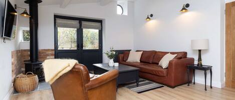 A modern living room with a leather sofa, a brown armchair, a black coffee table, and a fireplace.