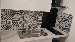 Une cuisine avec des armoires blanches, une hotte noire et des carreaux décoratifs sur le mur derrière l’évier ou la cuisinière.