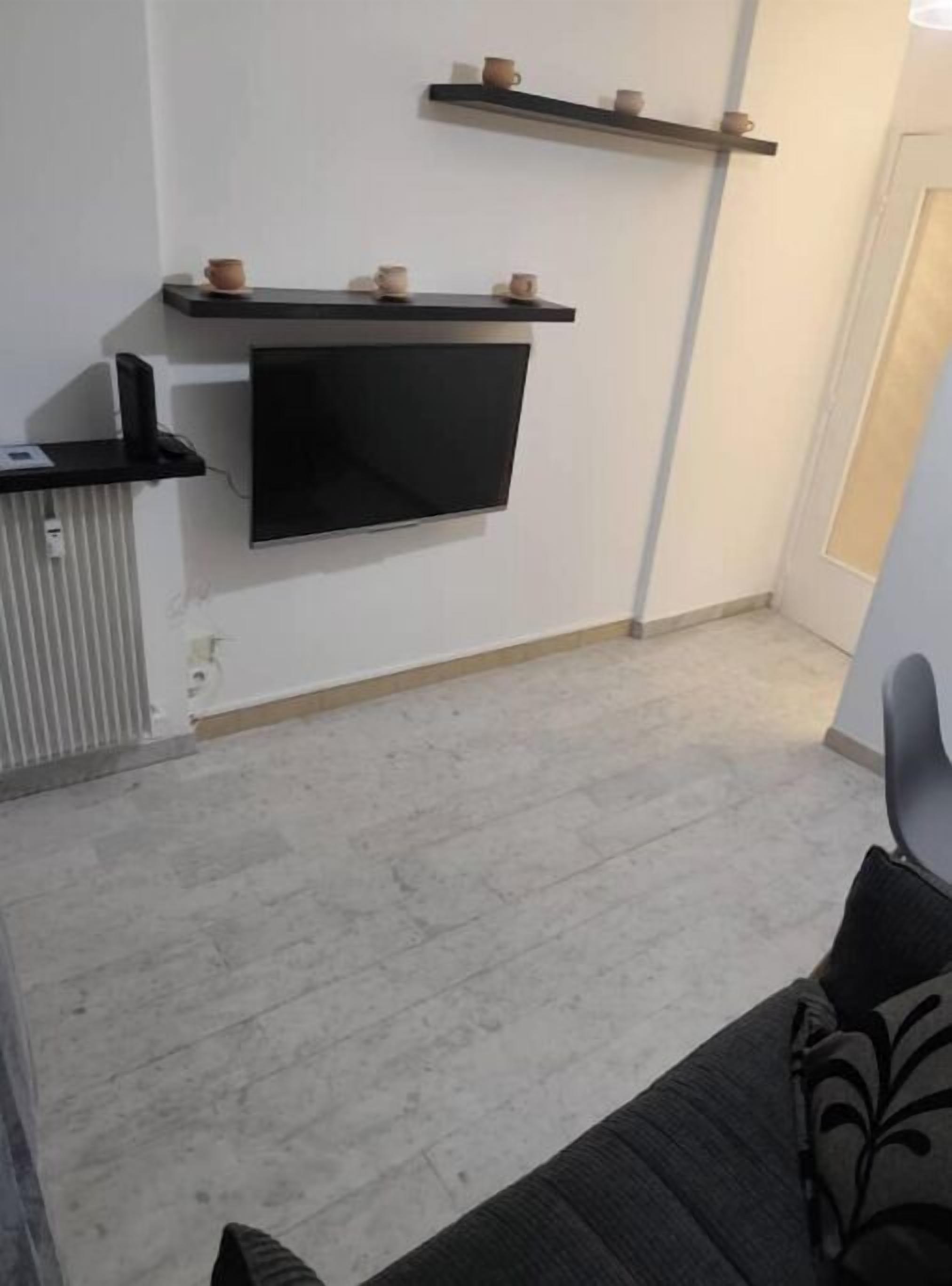 A modern living room with a flat-screen TV mounted on the wall, a small coffee table, and a sofa.