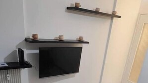 Un salon moderne avec un téléviseur à écran plat fixé au mur, une petite table basse et un canapé.