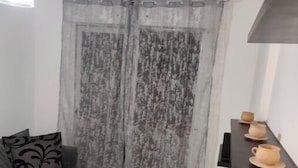 Un petit espace de vie compact, comprenant un canapé gris, une table basse et une étagère avec des tasses.