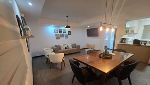 A modern living room with a sofa, dining table, and chairs. There is a kitchen area with a counter and appliances. - Cerca de Casa de Dios, Decocity Pradera Concepcion (Fraijanes)