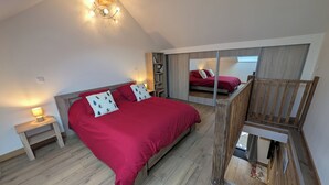 Ein Schlafzimmer mit einem großen Bett, Holzboden, einem Nachttisch und einer Deckenleuchte.