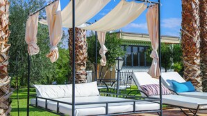 A bed with a canopy, two lounge chairs, and a patio area with a table and chairs. - Luxury villa heated pool (Marrakech)