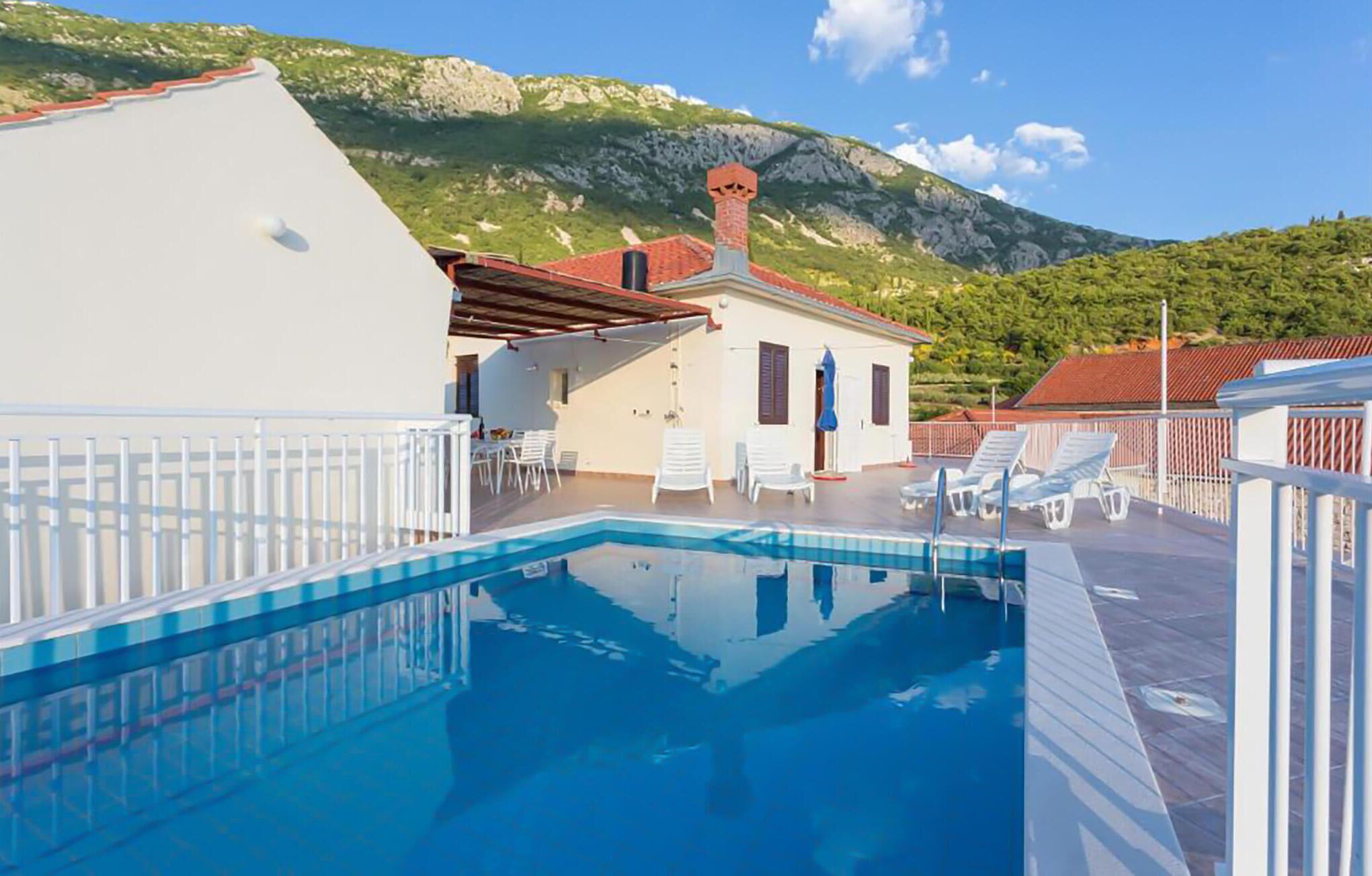 A swimming pool with a view of a mountain and a building with a red roof.