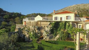 Una vila costanera amb un balcó que domina el mar, un jardí i un penya-segada rocosa.