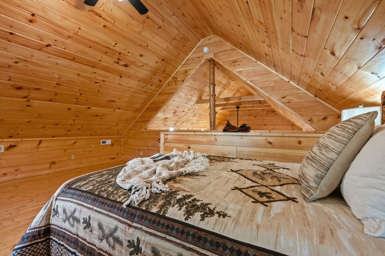 A cozy attic bedroom with wooden walls and a sloped ceiling.