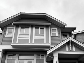 A two-story house with a gabled roof, multiple windows with shutters, and a garage door.