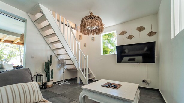 Un salon moderne avec un escalier, un téléviseur à écran plat et une table basse.