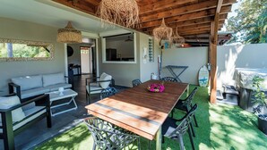 Une vaste terrasse dotée d’une table et de chaises en bois, entourée d’un canapé blanc et d’une table à manger.