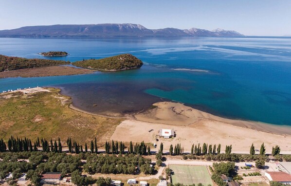 An aerial view of a coastal area with a sandy beach, a tennis court, and a small building. - 2 bedroom awesome home in Desne (Desne)