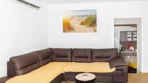 A living room with a brown sofa, a yellow throw blanket, and a painting of a beach.