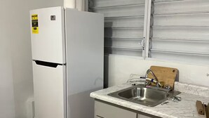 A compact kitchen with a white refrigerator, a sink, and a wooden cutting board. - 2 bedrooms in Hato Rey (San Juan)