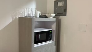 Un angolo cottura con forno a microonde, un piccolo frigorifero e un altro forno a microonde.