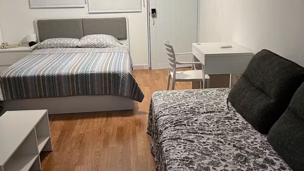 Una camera da letto con due letti, una scrivania, una sedia e un armadio.