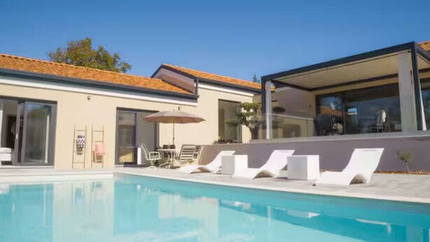 Ein moderner Poolbereich mit Liegestühlen und einer gläsernen Struktur.