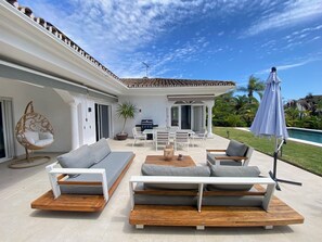 A modern outdoor living space with a pool, seating area, and a pergola. - Villa Acacias – A Peaceful Retreat with a Large Pool in Elviria (Marbella)