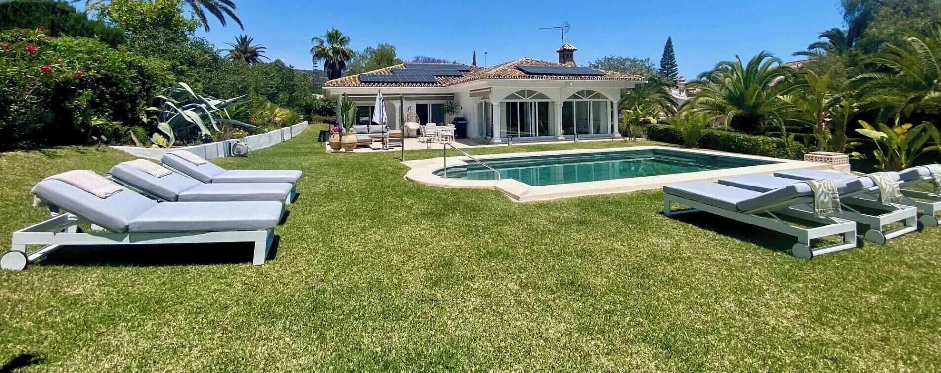 Ein Poolbereich mit Liegestühlen, einem Schwimmbecken und einem Haus mit einem Ziegeldach.