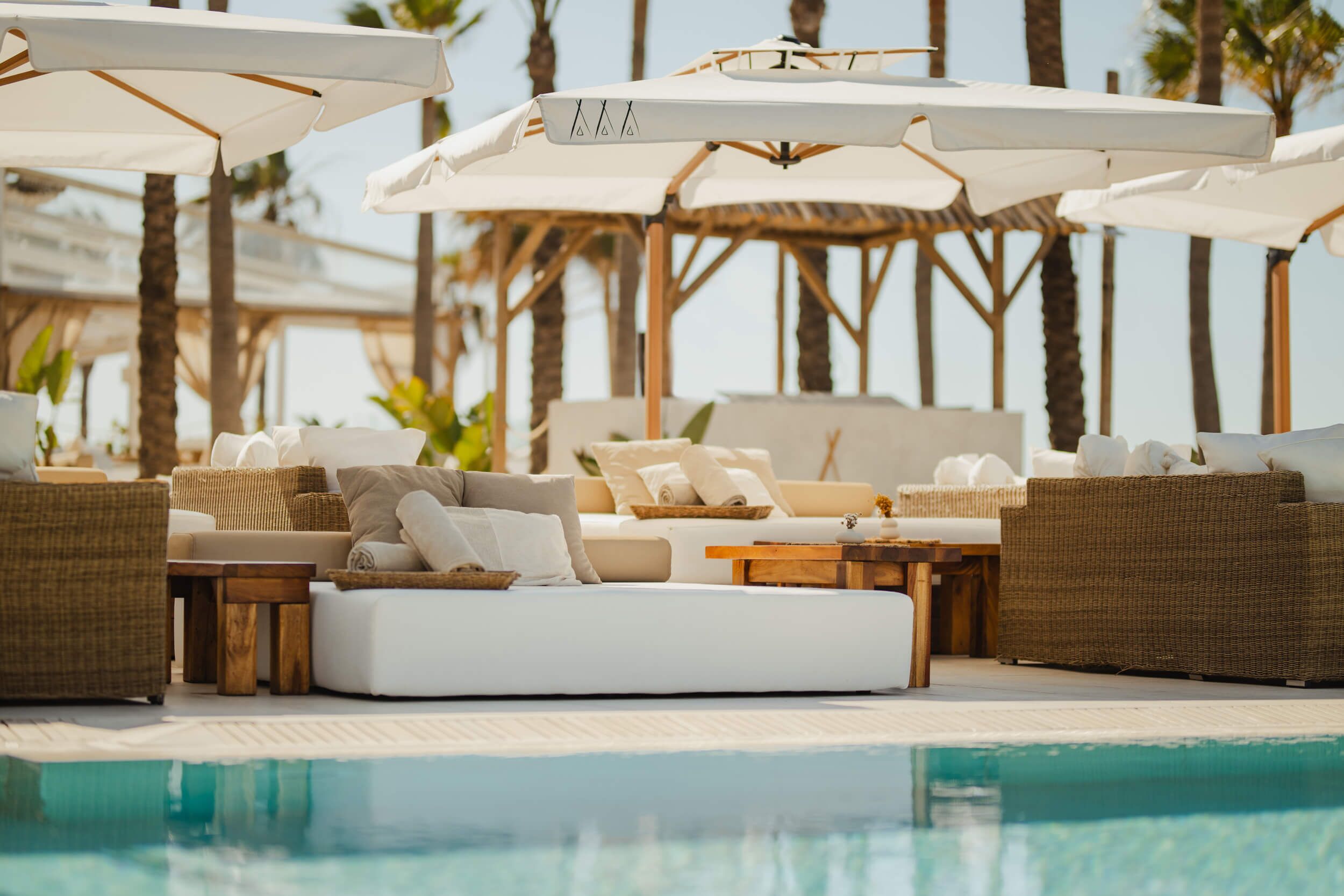 A poolside lounge area with sun loungers, umbrellas, and a wooden deck.
