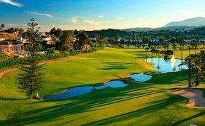A golf course with a pond, trees, and a mountain in the background. - Villa Acacias – A Peaceful Retreat with a Large Pool in Elviria (Marbella)