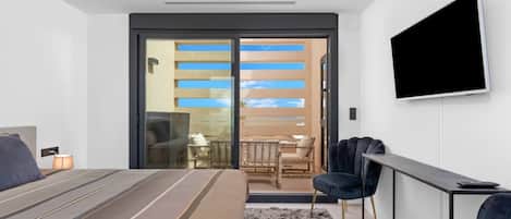 Habitación de hotel moderna con cama, televisión, escritorio y balcón con vistas.