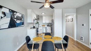A modern kitchen with white cabinets, a stainless steel refrigerator, and a ceiling fan.