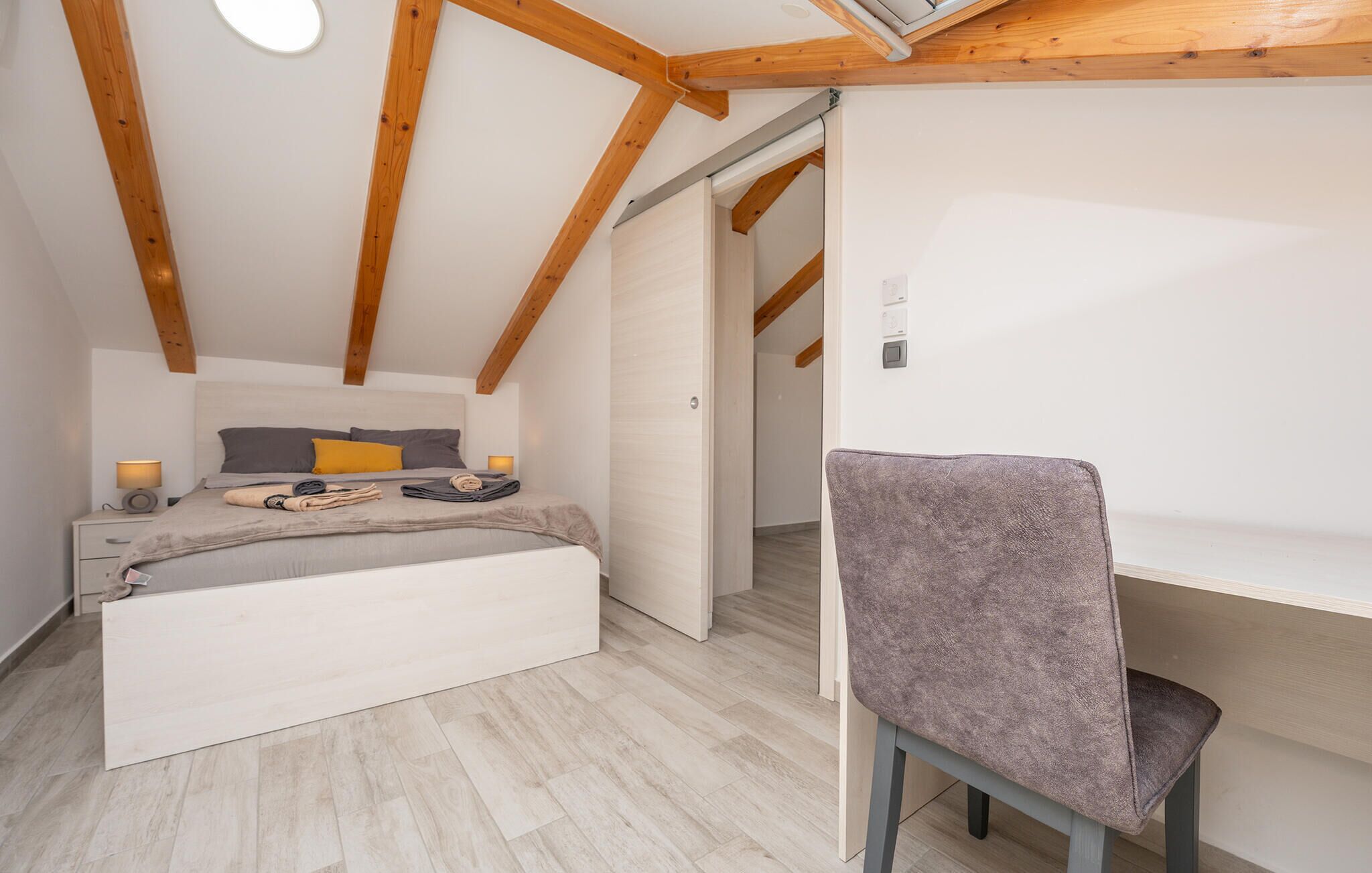 Une chambre à coucher comprenant un lit, des tables de chevet, une chaise et une structure de plafond en bois.