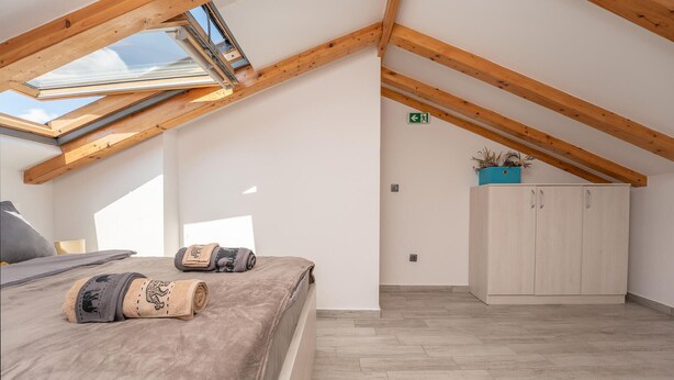 A room with a sloped ceiling, skylight, a bed with rolled towels, a wardrobe, and a potted plant. - 2 bedroom cozy apartment in Biograd (Biograd)