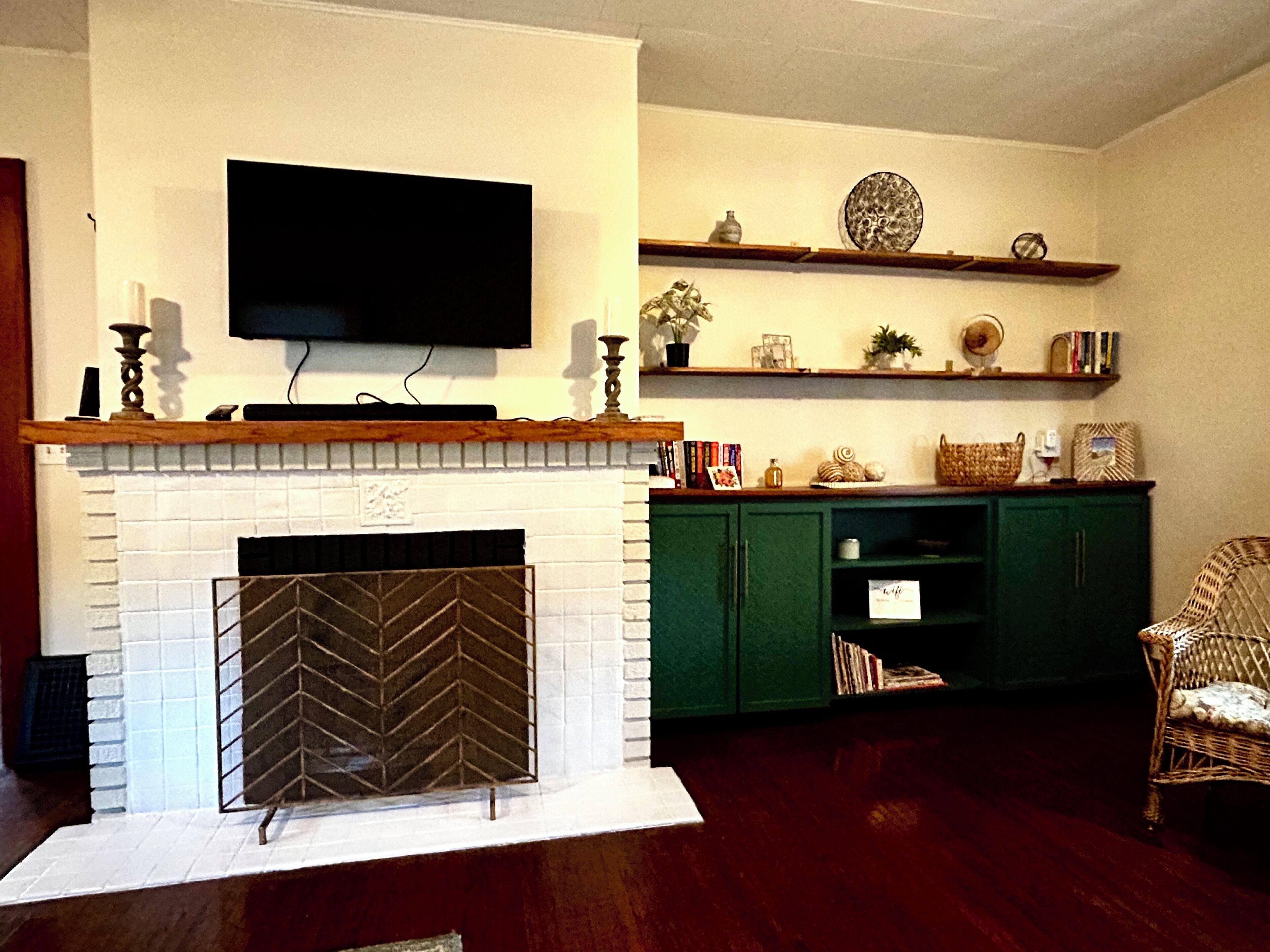 A living room with a fireplace, a flat-screen TV mounted above it, and a green cabinet below.