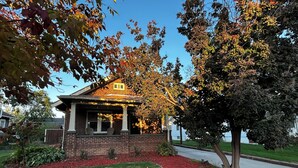A two-story house with a brick facade, a porch with two chairs, and a well-maintained lawn with red mulch borders. - 2 Bdrm home close to downtown Ames, Jack Trice, Hilton Coliseum & Stephens (Ames)