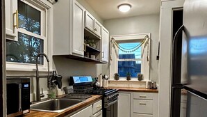 A modern kitchen with white cabinets, stainless steel appliances, a dishwasher, and a window with a view of the outside. - 2 Bdrm home close to downtown Ames, Jack Trice, Hilton Coliseum & Stephens (Ames)