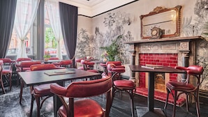 A restaurant with red leather chairs and tables, a fireplace, and a large mirror on the wall. - The Lawrence (Londonderry)