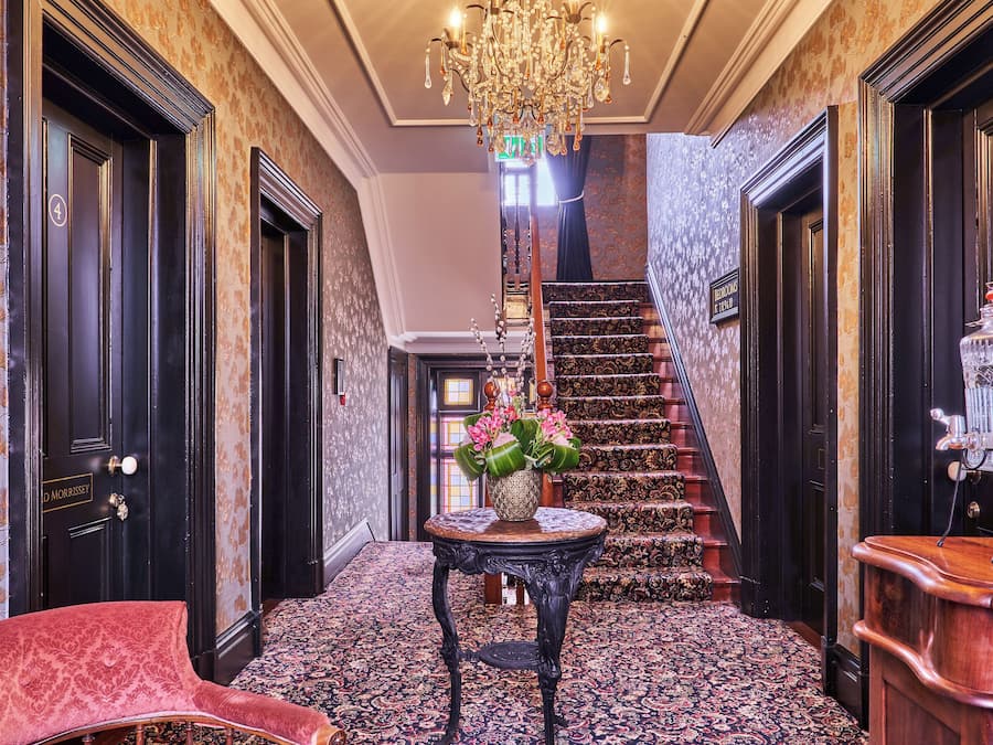 A grand hallway with a staircase, a chandelier, and a reception desk.