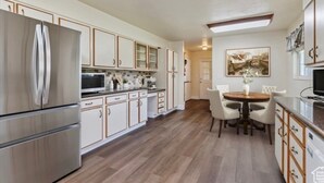 Una cocina moderna con electrodomésticos de acero inoxidable, armarios blancos y un comedor con una mesa redonda y sillas.