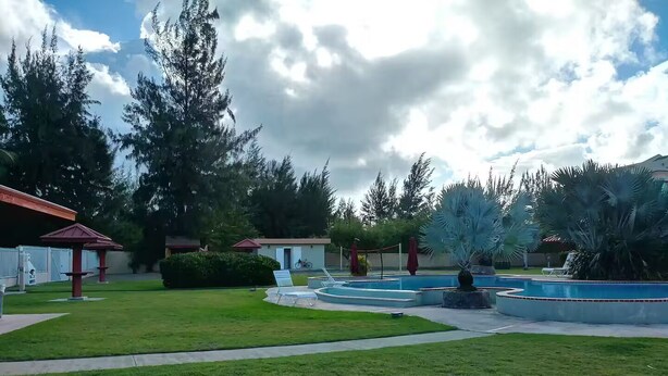 Un espace extérieur aménagé avec une piscine, des chaises longues et un coin salon abrité.